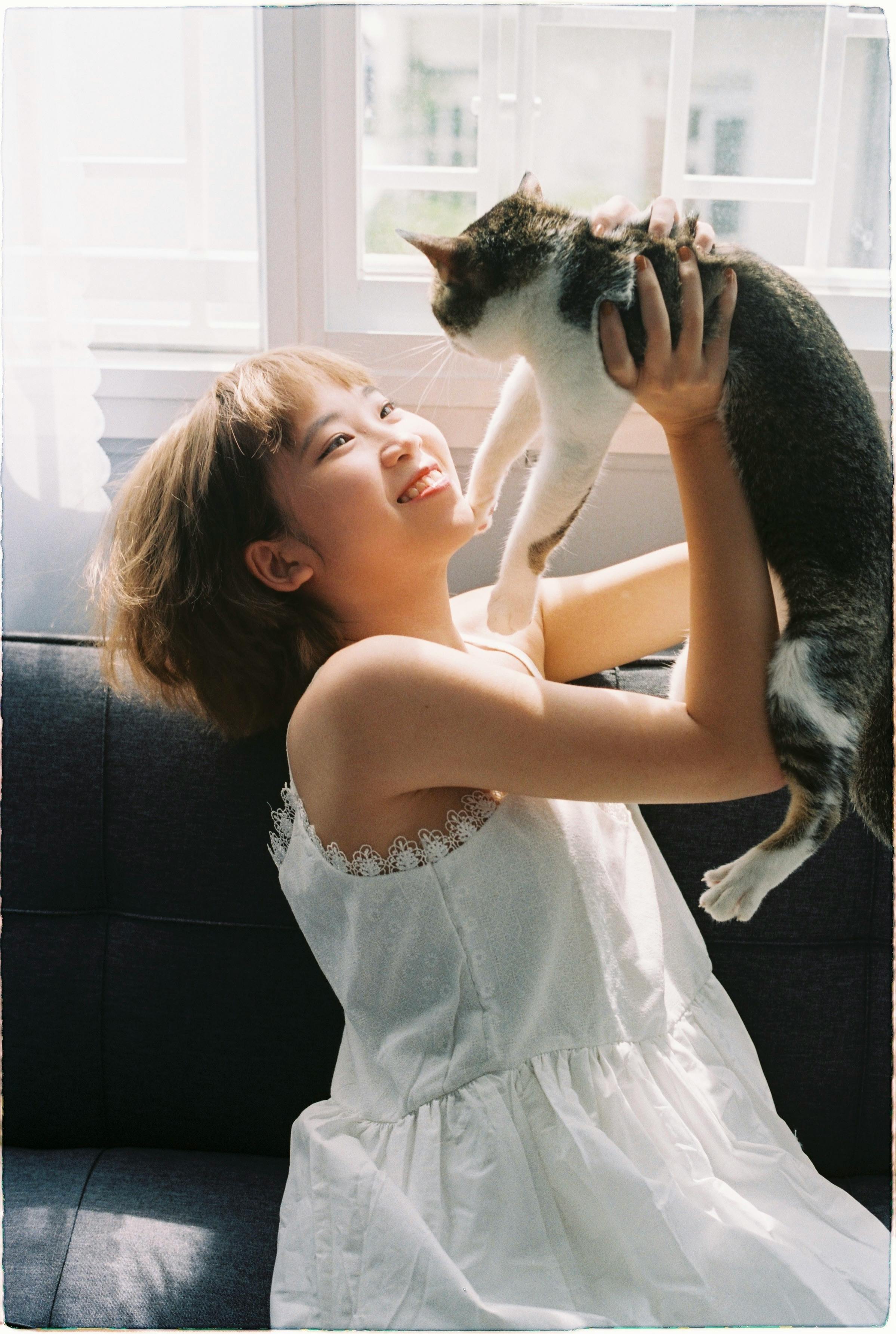 happy girl with a white dress carrying a cat